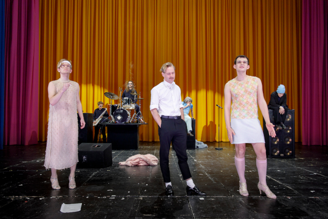 Drei Männer vor einem gelebn Vorhang